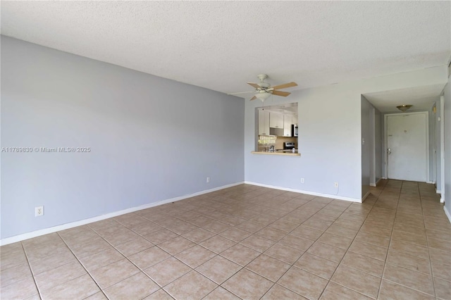 spare room featuring a textured ceiling, ceiling fan, light tile patterned floors, and baseboards