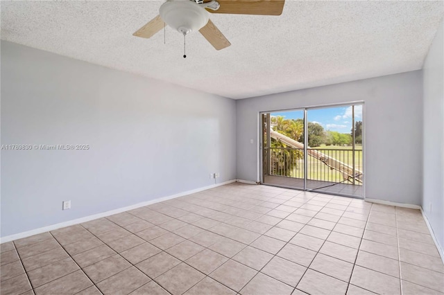 spare room featuring light tile patterned floors, a textured ceiling, a ceiling fan, and baseboards