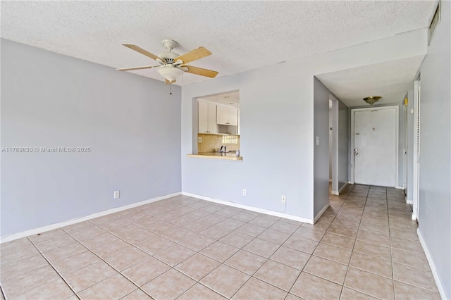 spare room with baseboards, light tile patterned floors, ceiling fan, and a textured ceiling
