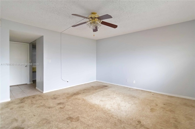 carpeted spare room with baseboards, ceiling fan, and a textured ceiling