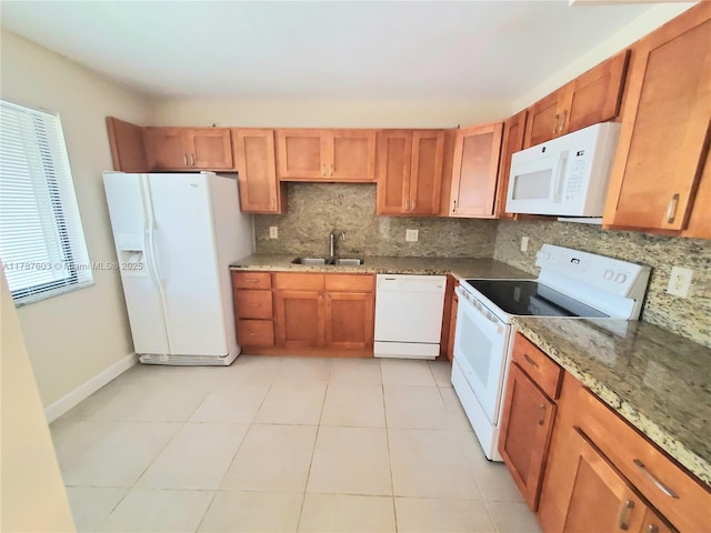 kitchen featuring brown cabinets, decorative backsplash, a sink, and white appliances