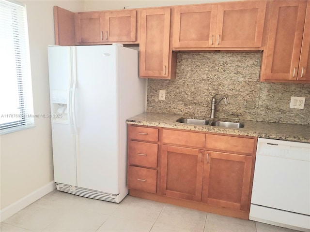 kitchen with tasteful backsplash, light stone countertops, a sink, and white appliances