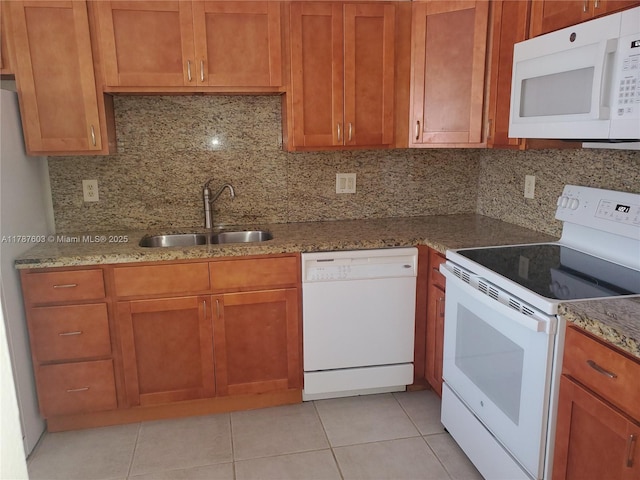 kitchen with light stone countertops, white appliances, a sink, and tasteful backsplash
