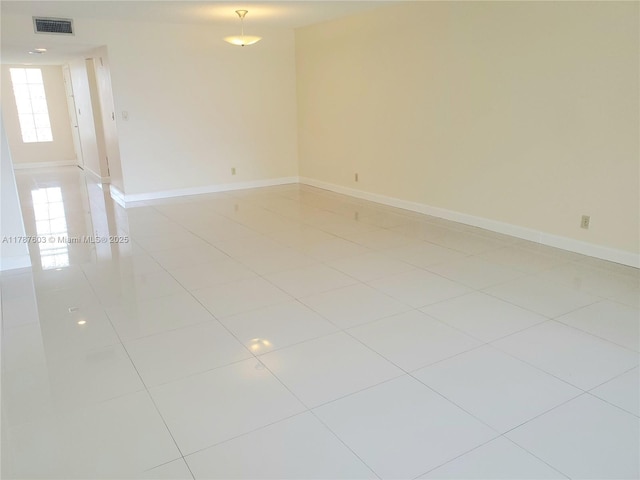 empty room featuring baseboards, visible vents, and light tile patterned floors