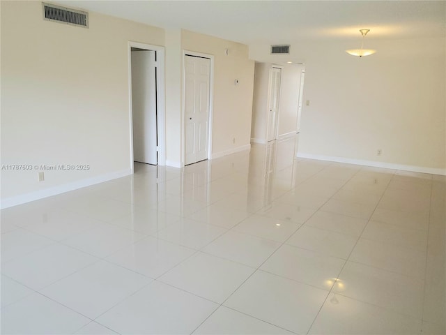 empty room with visible vents, baseboards, and light tile patterned floors