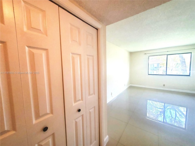 empty room featuring tile patterned floors, baseboards, and a textured ceiling