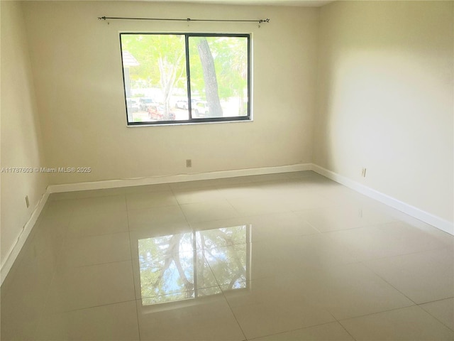 tiled empty room featuring baseboards