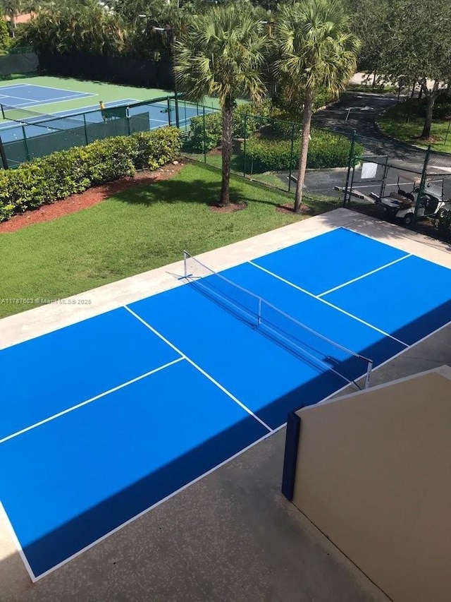 view of tennis court featuring a lawn, fence, and community basketball court