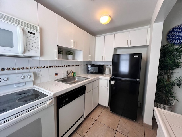 kitchen featuring white cabinetry, a sink, black appliances, tile countertops, and backsplash