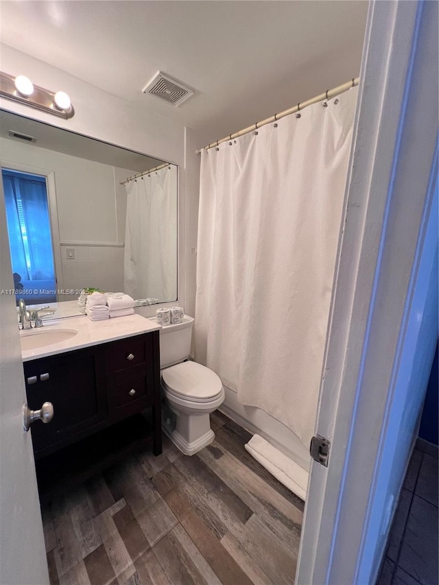 full bathroom featuring toilet, vanity, visible vents, and wood finished floors
