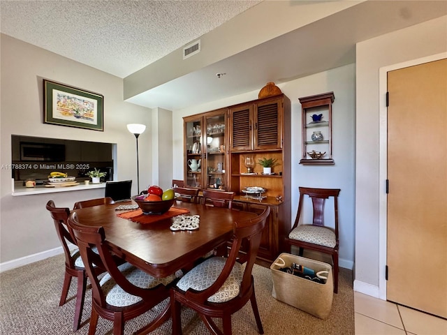 dining room featuring baseboards, visible vents, a textured ceiling, and light tile patterned floors