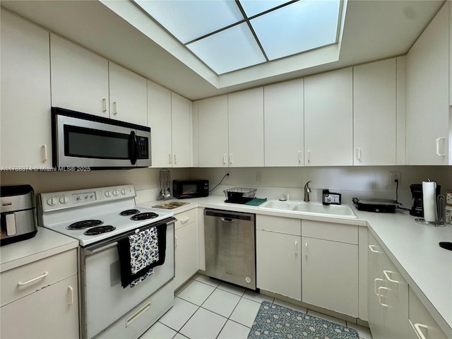 kitchen with white cabinets, a sink, appliances with stainless steel finishes, light countertops, and light tile patterned floors