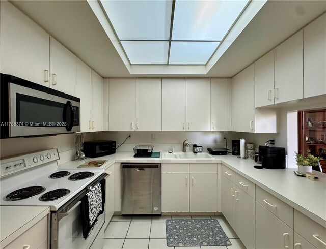 kitchen featuring a sink, light tile patterned floors, appliances with stainless steel finishes, light countertops, and white cabinetry