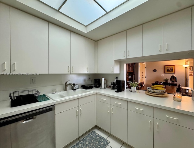 kitchen featuring a sink, a skylight, light tile patterned floors, dishwasher, and light countertops