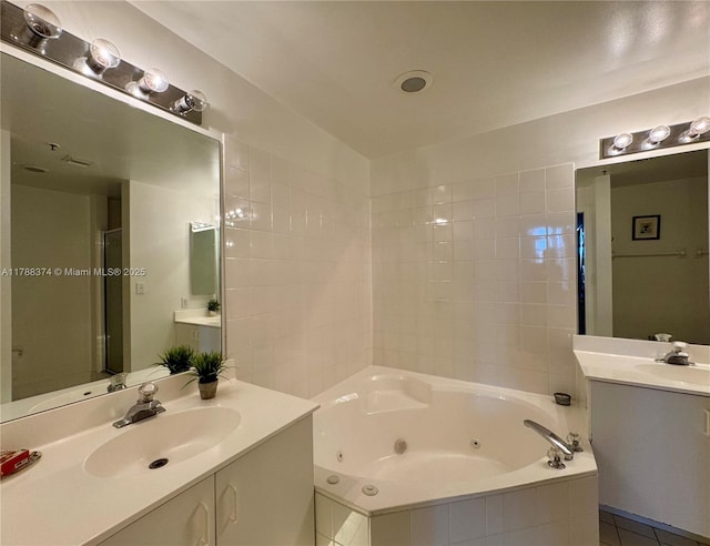 full bath featuring two vanities, a sink, and a tub with jets
