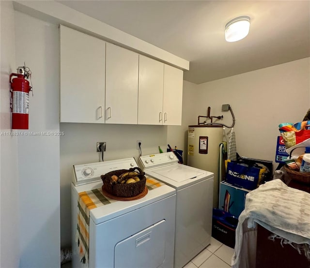 laundry area with electric water heater, light tile patterned flooring, washer and clothes dryer, and cabinet space