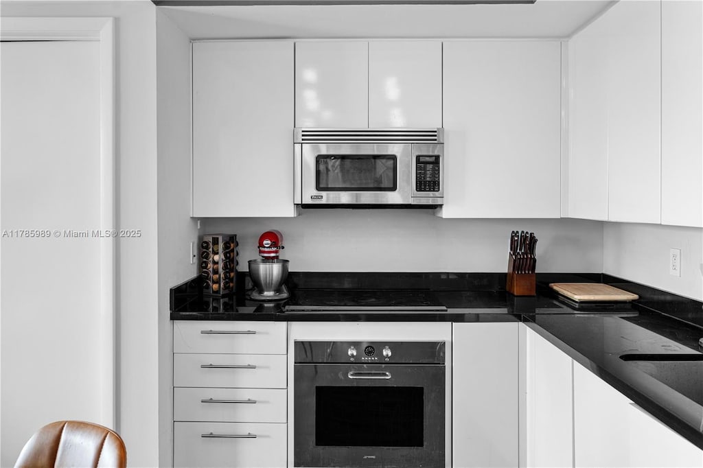 92 SW 3rd St Unit 4604, Miami, FL 33130 - kitchen with stainless steel appliances, white cabinetry, dark countertops, modern cabinets, and a sink