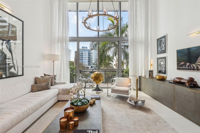tiled living room featuring a chandelier, a towering ceiling, and floor to ceiling windows