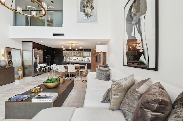 living room featuring a high ceiling, a notable chandelier, and visible vents