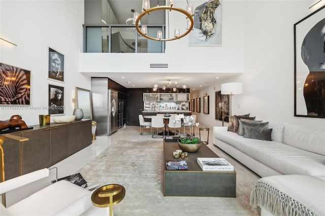 living room with visible vents, a towering ceiling, and an inviting chandelier