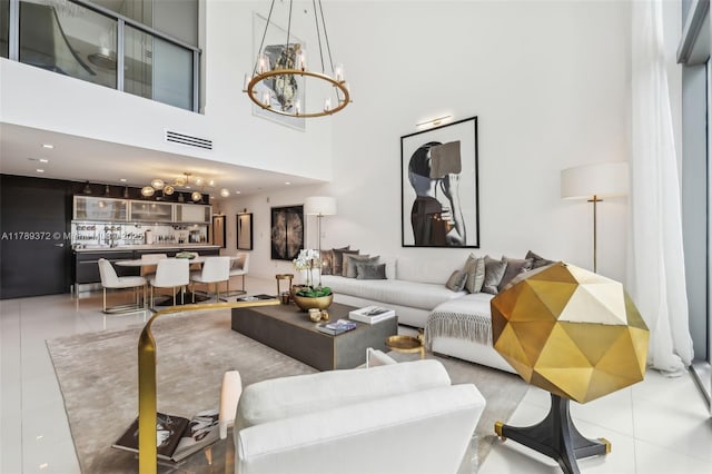 tiled living area with visible vents, a towering ceiling, and an inviting chandelier