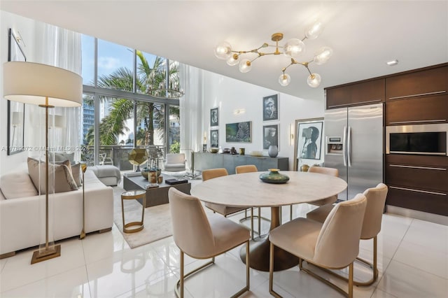 dining area featuring light tile patterned flooring, a high ceiling, floor to ceiling windows, and a notable chandelier