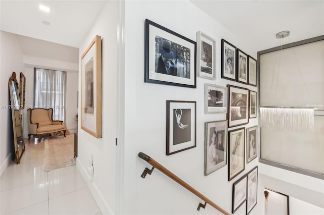 corridor with tile patterned floors, baseboards, and an upstairs landing