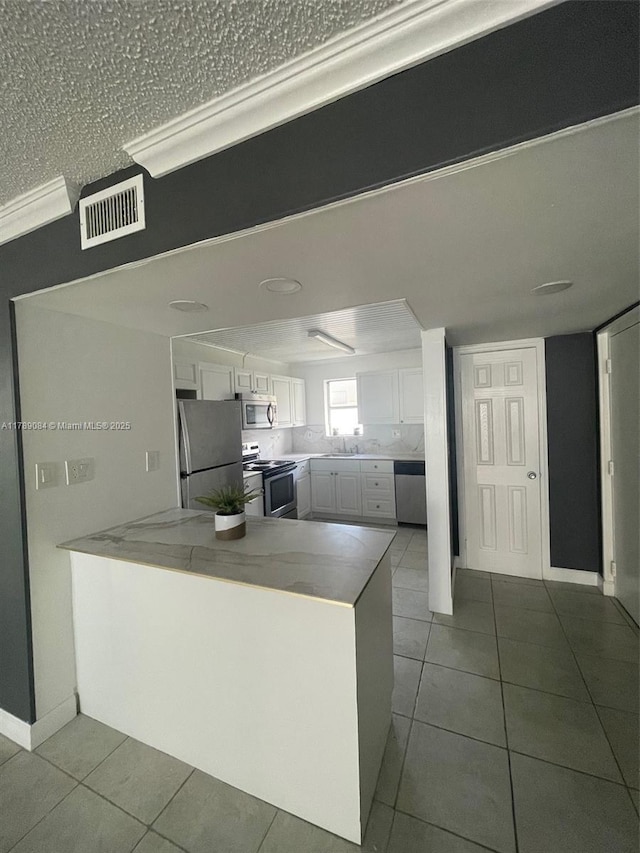600 NE 25th St Unit 60, Miami, FL 33137 - kitchen featuring stainless steel appliances, visible vents, tile patterned flooring, and white cabinetry