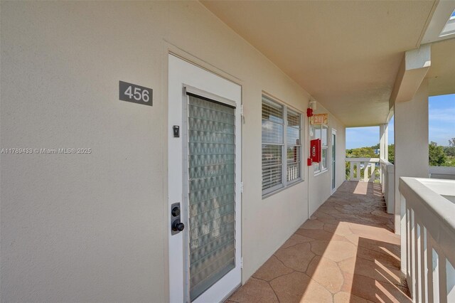 property entrance featuring a balcony and stucco siding