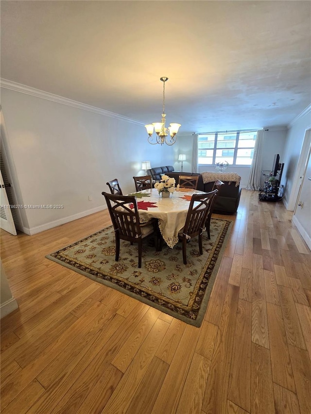 5825 Collins Ave Unit 2D, Miami Beach, FL 33140 - dining space featuring baseboards, ornamental molding, a chandelier, and light wood-style flooring