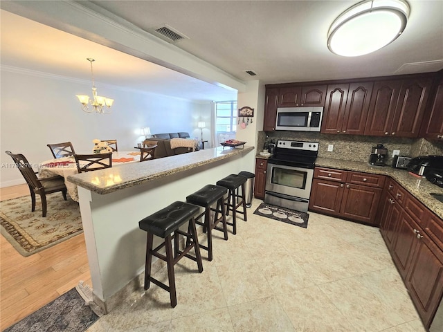 5825 Collins Ave Unit 2D, Miami Beach, FL 33140 - kitchen with stainless steel appliances, tasteful backsplash, a breakfast bar, visible vents, and ornamental molding