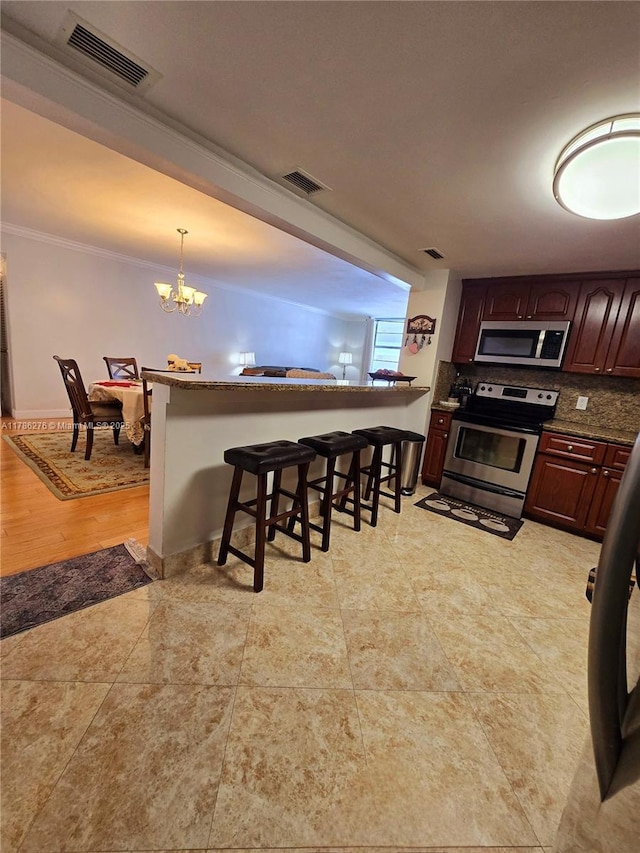 5825 Collins Ave Unit 2D, Miami Beach, FL 33140 - kitchen with a chandelier, a breakfast bar, visible vents, ornamental molding, and appliances with stainless steel finishes