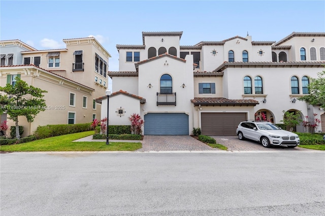 view of front of house featuring stucco siding, an attached garage, decorative driveway, and a tiled roof