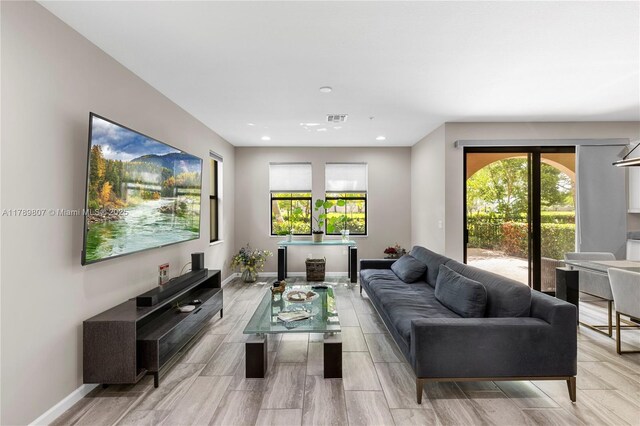 living area with baseboards, a wealth of natural light, and recessed lighting