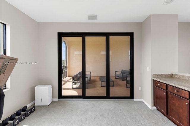 doorway featuring light colored carpet, baseboards, and visible vents