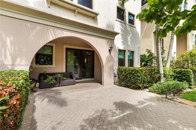 view of exterior entry with a patio area and stucco siding