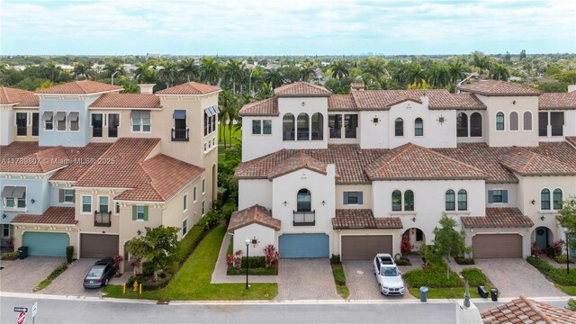 view of front facade with a residential view, a tiled roof, driveway, a garage, and stucco siding
