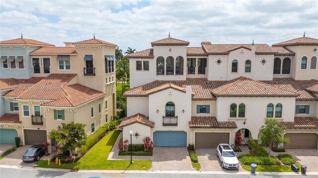 view of front of home featuring stucco siding, driveway, a tiled roof, and a garage