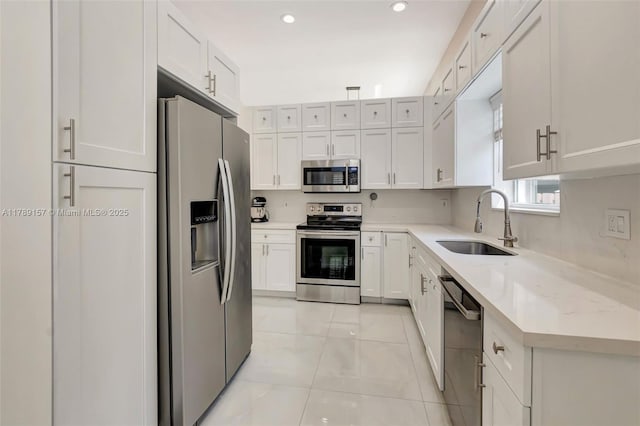 kitchen featuring white cabinets, stainless steel appliances, a sink, and light tile patterned floors