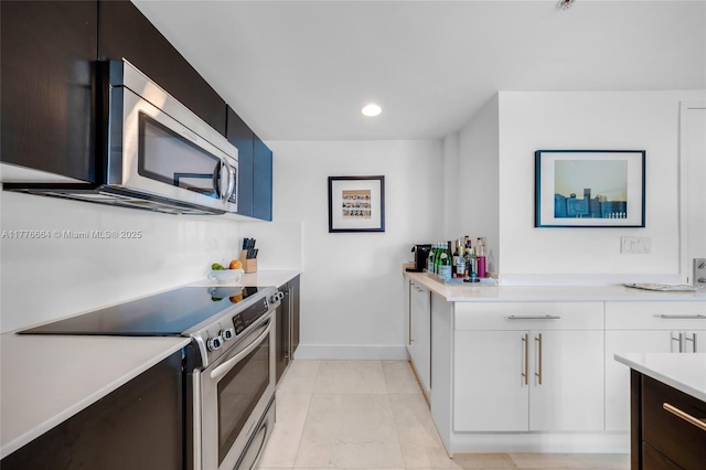 665 NE 25th St Unit 1201, Miami, FL 33137 - kitchen featuring marble finish floor, white cabinetry, light countertops, baseboards, and appliances with stainless steel finishes
