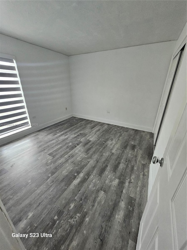 unfurnished room featuring wood finished floors, a textured ceiling, and baseboards