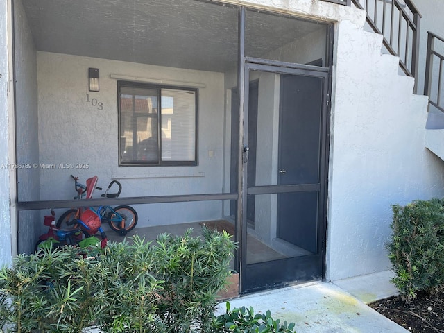 doorway to property featuring stucco siding