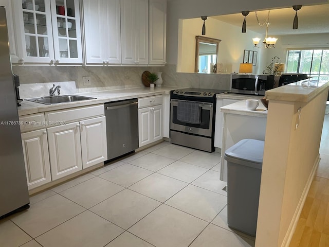 kitchen with light countertops, a sink, a peninsula, appliances with stainless steel finishes, and white cabinetry