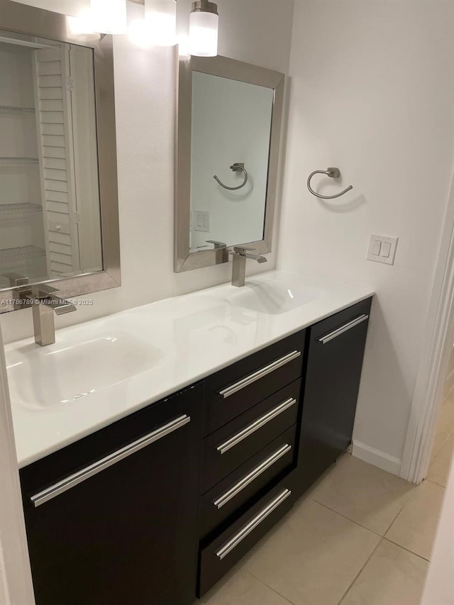 bathroom featuring double vanity, tile patterned floors, baseboards, and a sink
