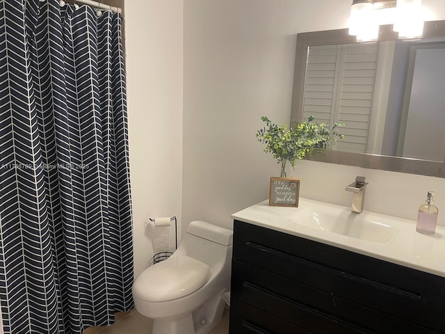 bathroom with toilet, vanity, and tiled shower