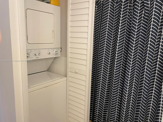 clothes washing area featuring stacked washer / dryer and laundry area