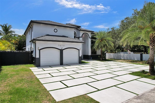 mediterranean / spanish house featuring driveway, a tile roof, fence, an attached garage, and stucco siding