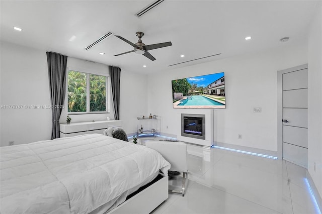 bedroom with a ceiling fan, visible vents, tile patterned flooring, a glass covered fireplace, and recessed lighting