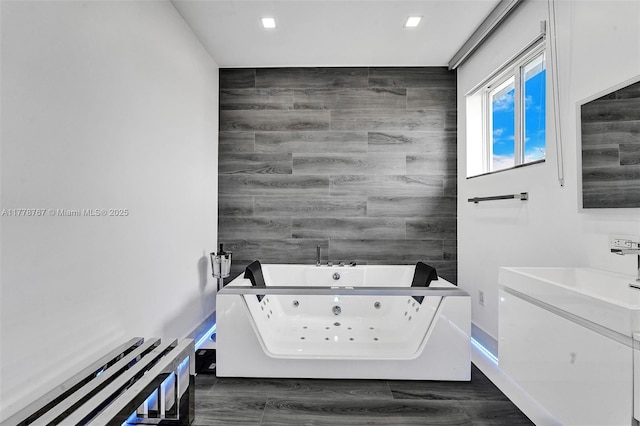 full bath featuring a whirlpool tub, tile walls, an accent wall, and vanity