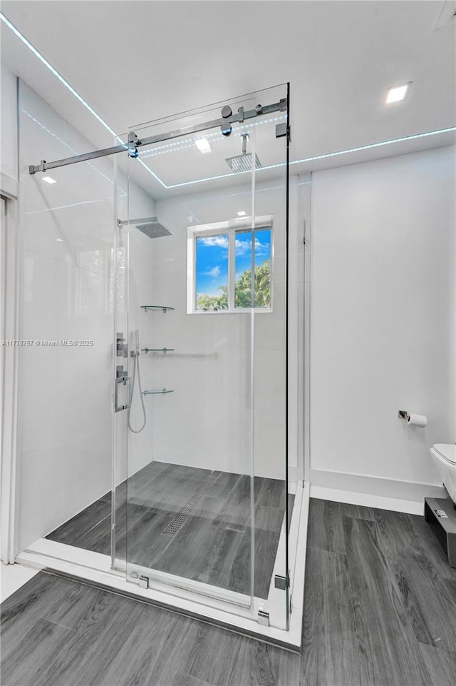 bathroom with baseboards, a shower stall, toilet, and wood finished floors